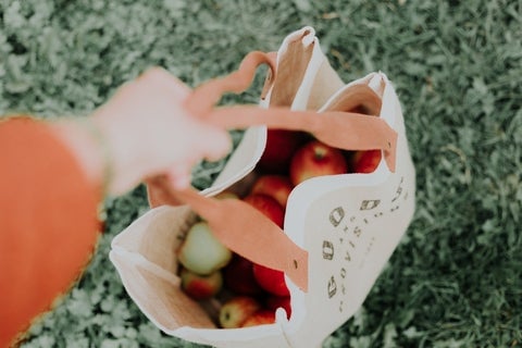 A women holds an eco tote bag filled with fruit