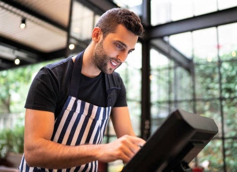 waiter wearing apron using cash register in restaurant