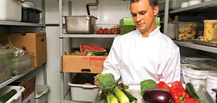 handsome young chef calculates food costs in restaurant larder