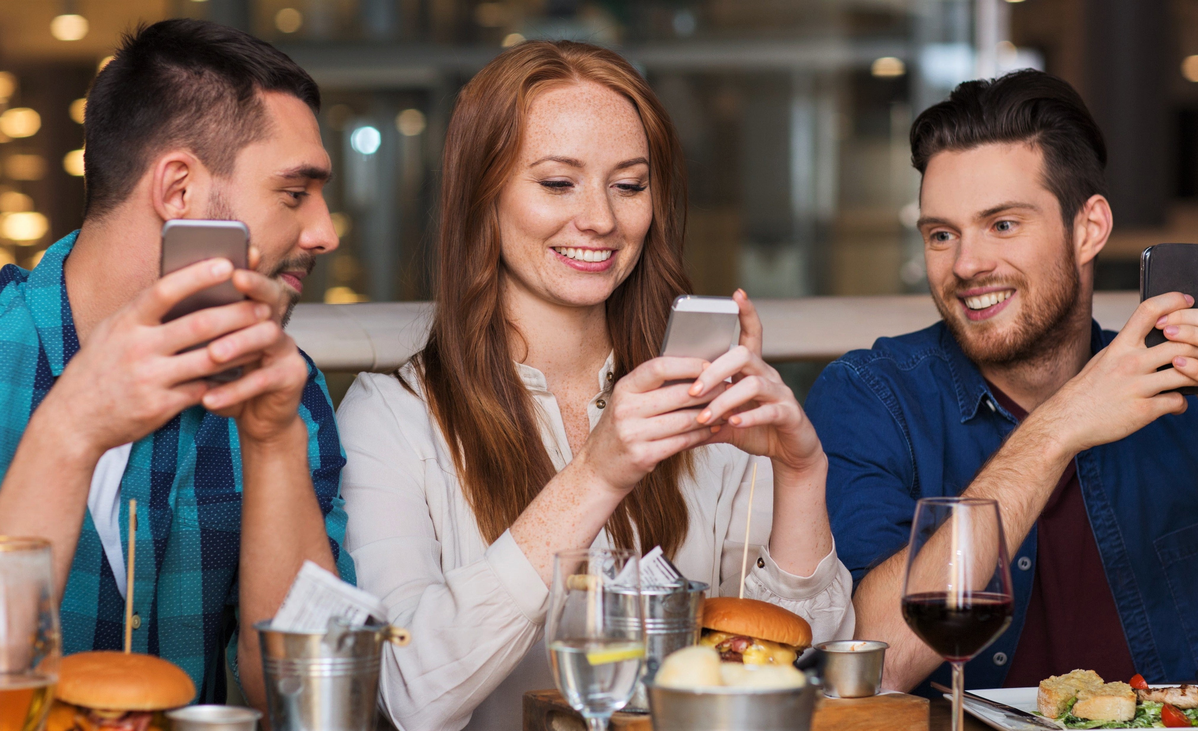 young people looking at digital menus on smartphones in restaurant