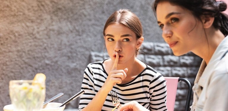 pair of young women conspiring to dine and dash in restaurant