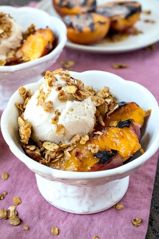 Grilled peaches with vanilla ice cream in a white porcelain bowl.