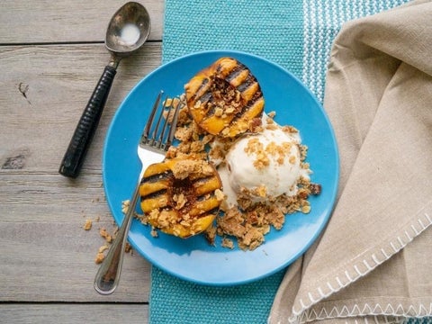 Overhead shot of peach cobbler and vanilla ice cream on a blue plate. 