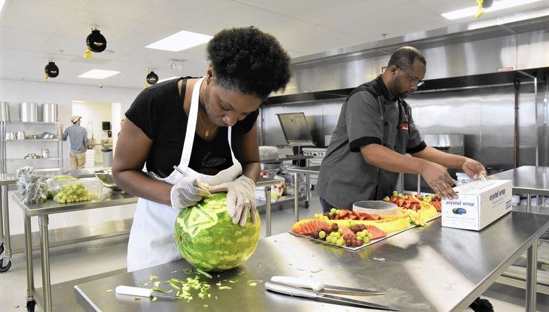 woman of color prepares organic ingredients for cooking in shared incubator kitchen