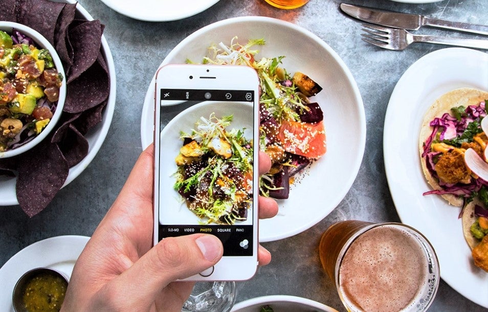 instagram influencer uses iphone to post food in restaurant
