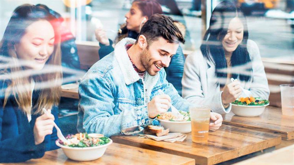 young man eating in restaurant with two female friends