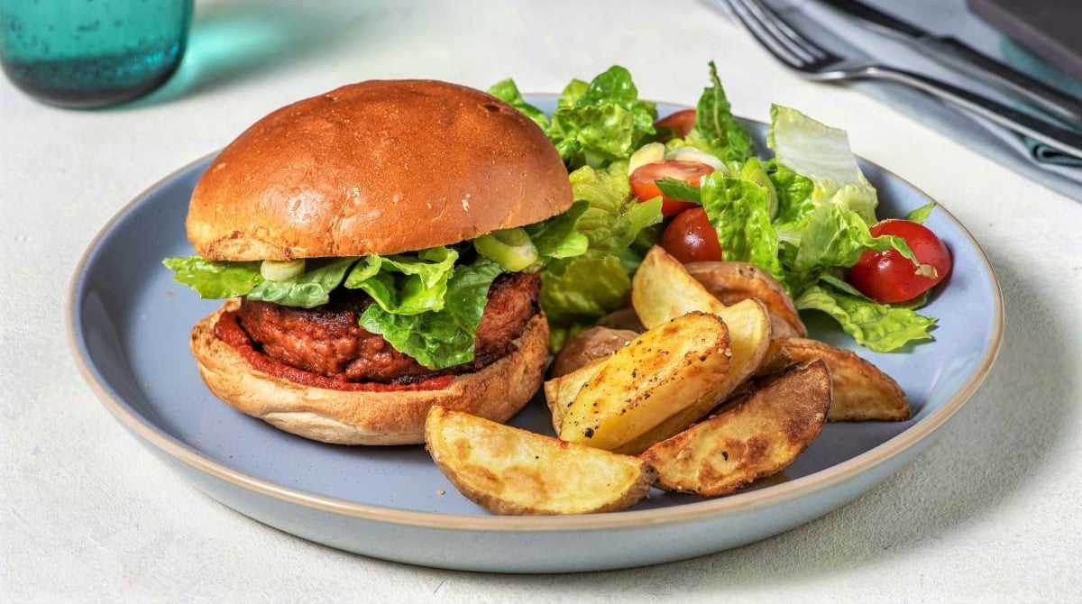 plant-based burger and potato wedges served with fresh green salad