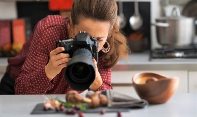 woman photographs exciting restaurant dish with dslr camera