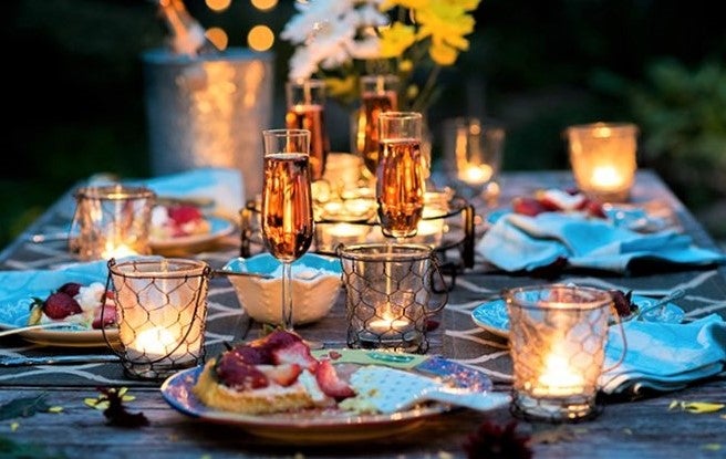 elegant restaurant dining table lit by candles and laid with champagne flutes