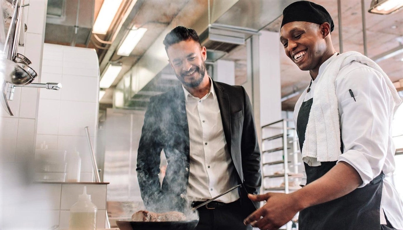 friendly hands-on manager shares conversation with happy chef in restaurant