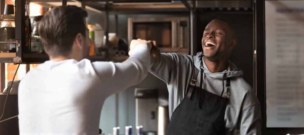 black restaurant owner greets regular customer with fist bump