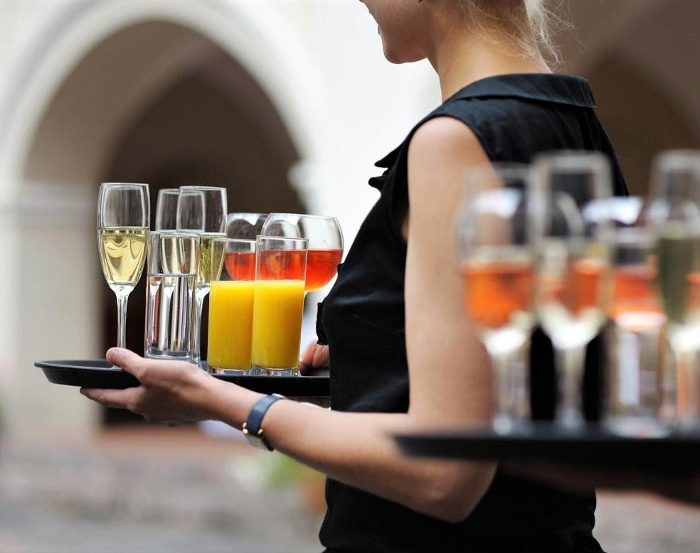 waitress carries tray of drinks to upsell products in outdoor restaurant