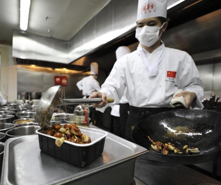 chefs work in ghost kitchen for asian restaurant during pandemic