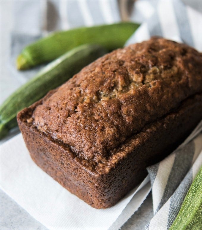 zucchini bread fresh from the oven with fresh zucchini behind it