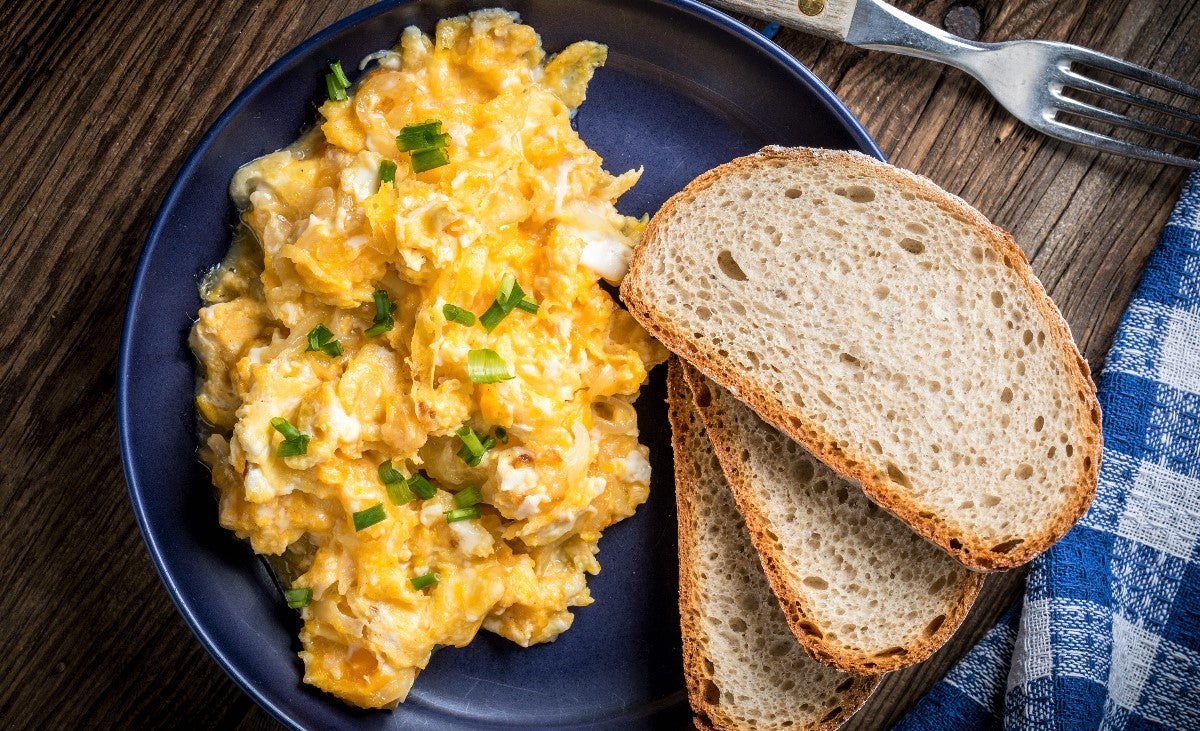 deluxe serving of scrambled eggs with chives served on multigrain toast